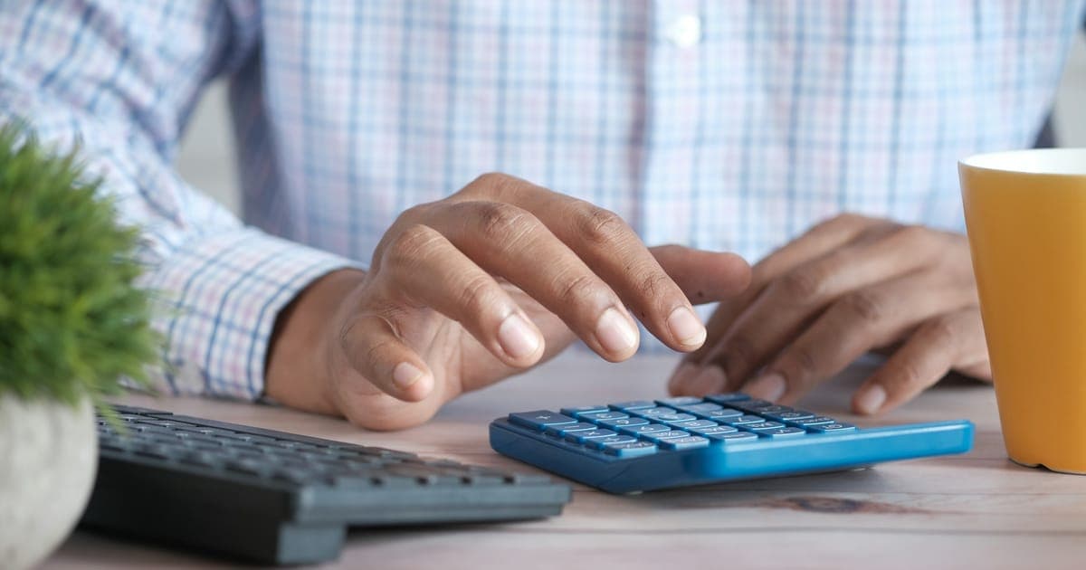 Pessoa fazendo contas na calculadora sobre relatórios