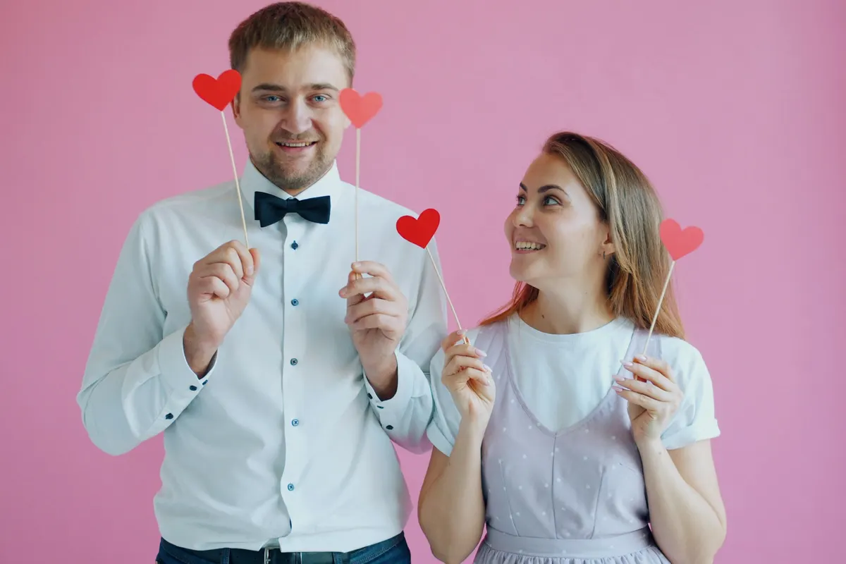 Casal posando com plaquinhas de cabine de fotos