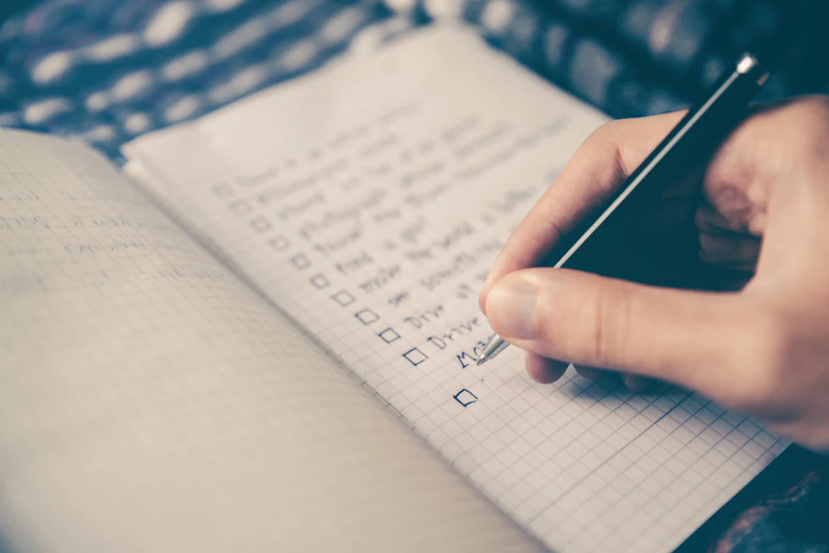 Pessoa escrevendo uma lista de tarefas no caderno