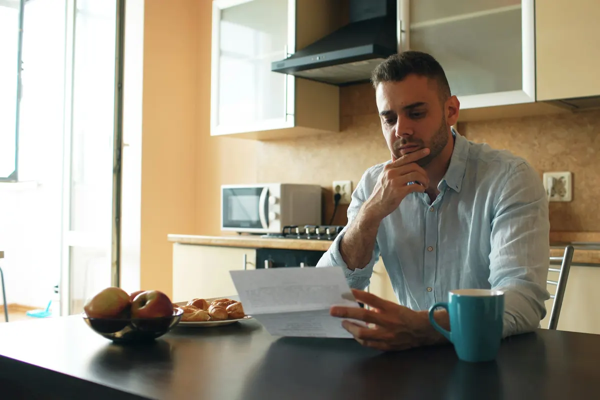 Homem conferindo papéis na cozinha