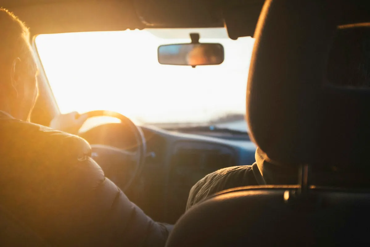 Pessoa dirigindo o carro na estrada ao entardecer